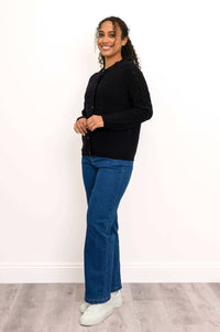 Side view of a woman in a black cable knit cardigan paired with jeans