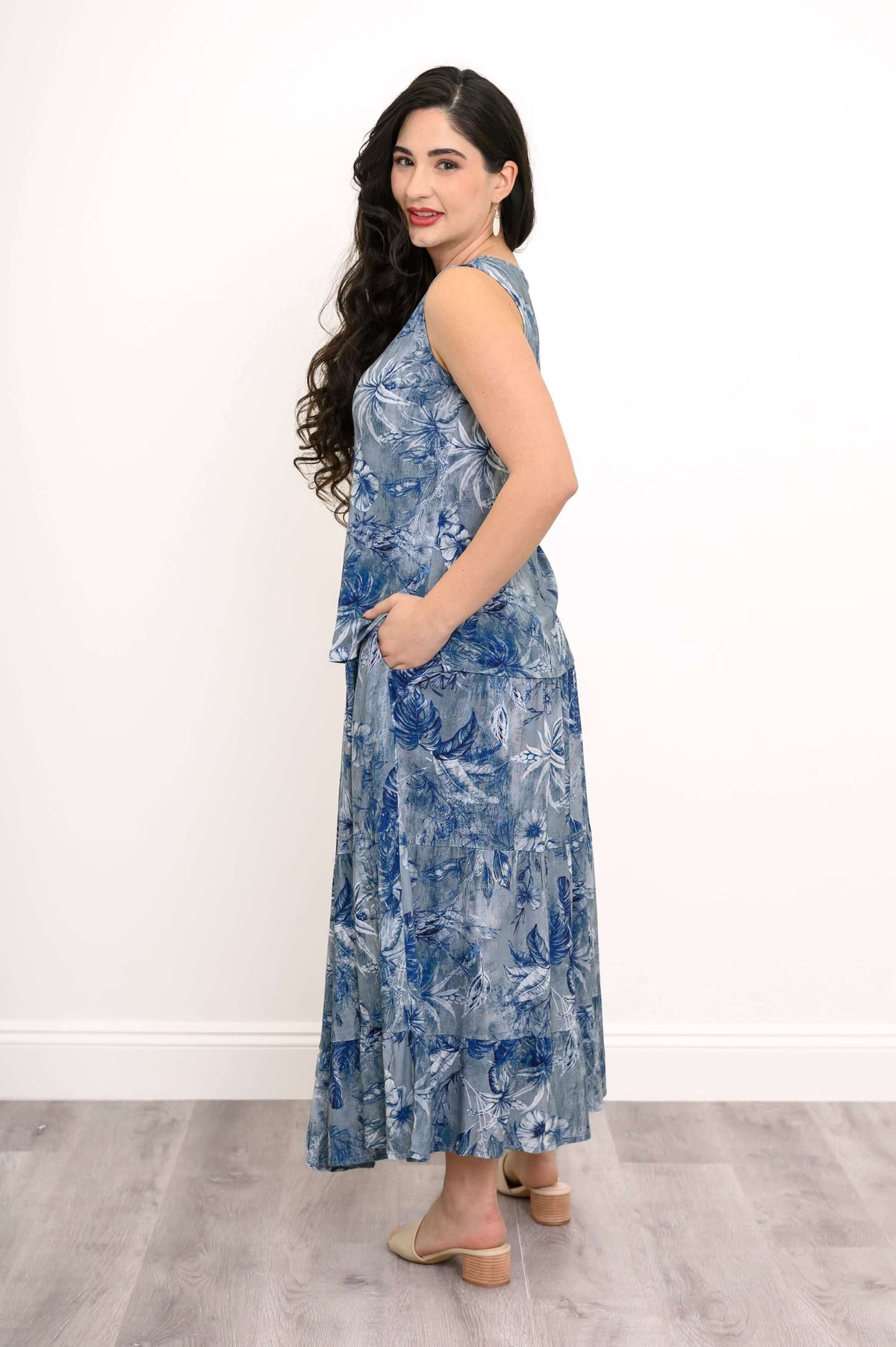 Side view of woman in blue floral tank top and matching skirt with hand in pocket
