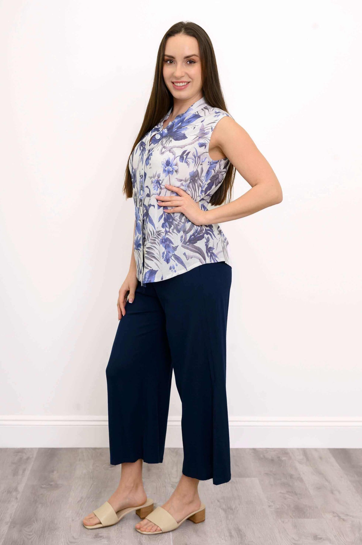 Side angle of woman modeling blue floral blouse paired with navy pants