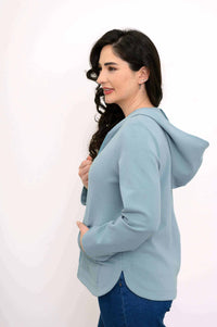 Side view of woman modeling light blue hoodie jacket showing hood and slitted hem