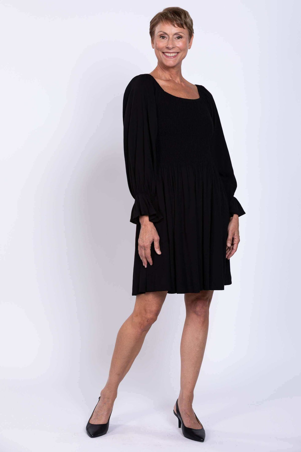 Side view of a woman in a black shirred bodice dress with full skirt