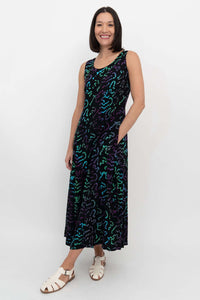 Side view of woman in sleeveless scoop neck black dress with hand in pocket