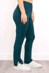 Side view of teal bamboo pants highlighting ankle slit detail and elastic waist, styled with white sneakers