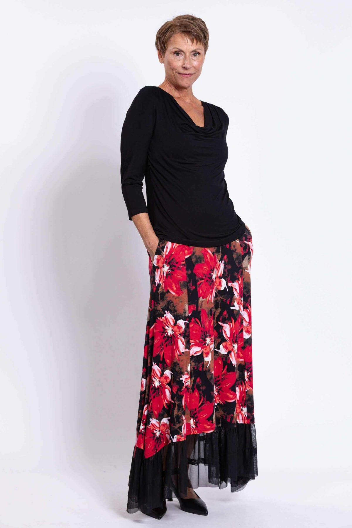 Side angled view of woman in black top and red floral Vera Maxi Skirt with pockets and mesh hem