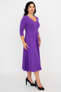 Side view of a woman in a purple midi dress with three-quarter sleeves and black heels