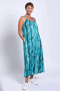 Side view of woman in aqua blue jumpsuit with hands in pockets
