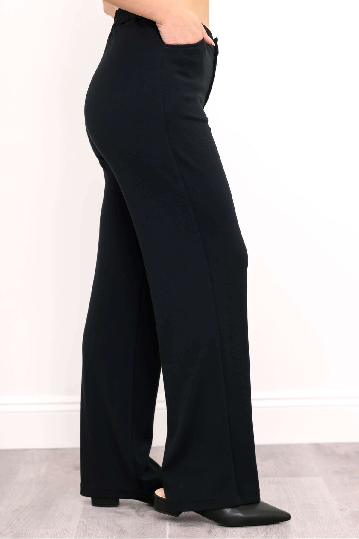 Side profile of black high-waisted pants showing pocket detail