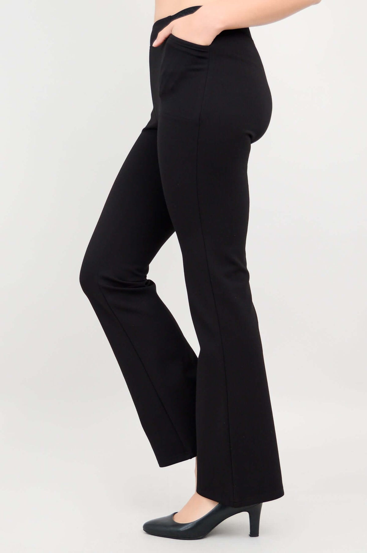 Side view with model's hand in pocket, displaying sleek fit of black pants