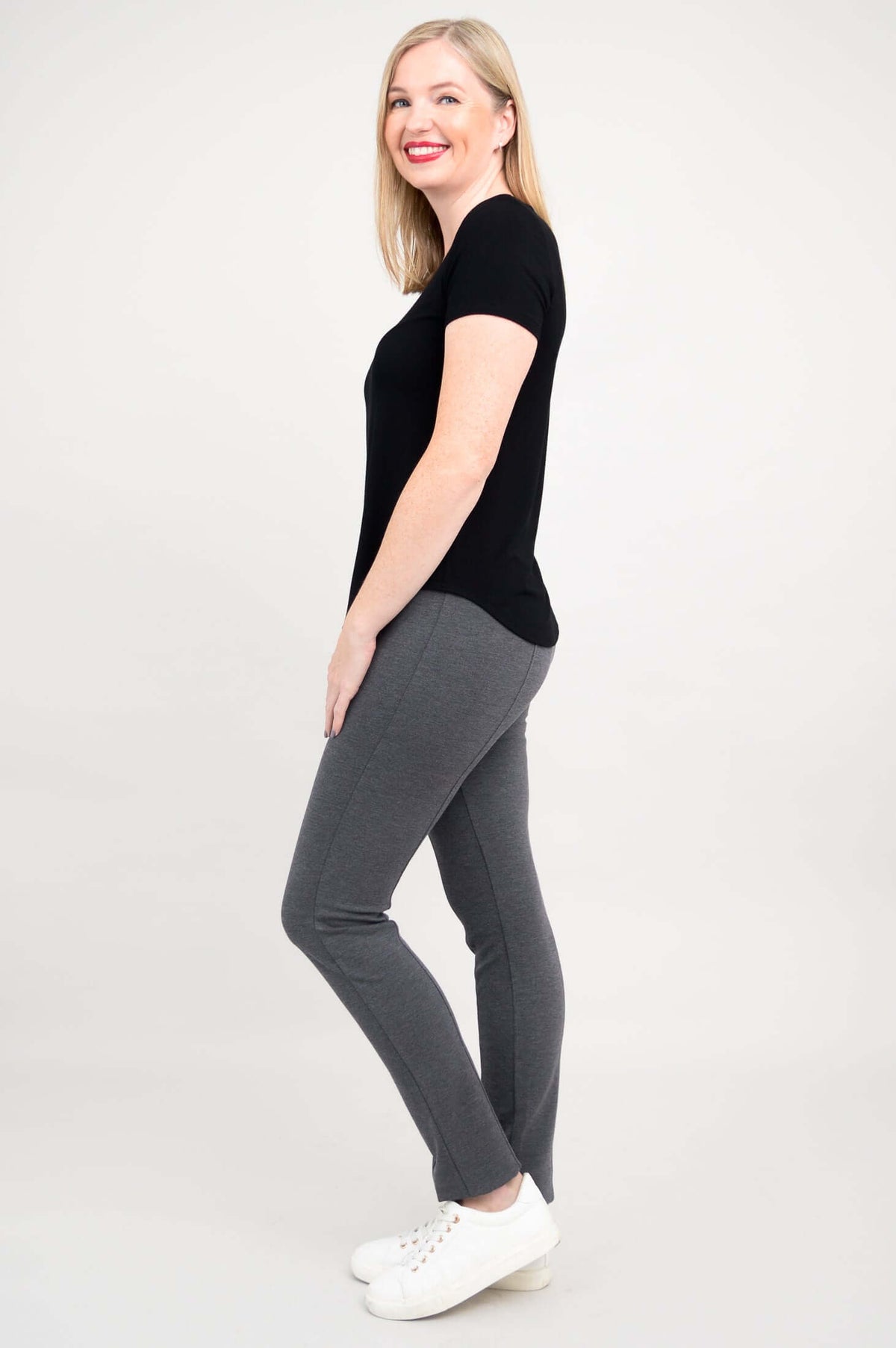 Side view of woman in black scoop neck tee and grey pants