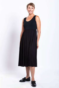 Side view of a woman smiling in a black sleeveless empire waist midi dress