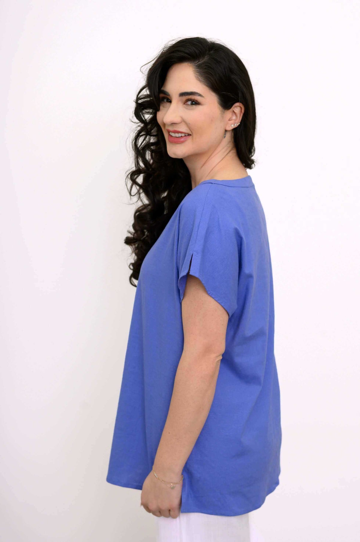 Side view of model showcasing cap dolman sleeves and shoulder slit of blue Aria Tee