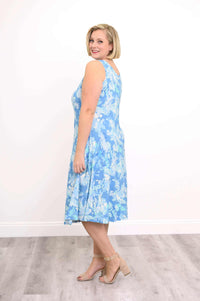 Woman in blue abstract print tank dress, turned sideways and smiling