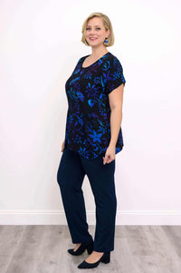 Side view of woman in black floral print curved-hem tunic and navy pants