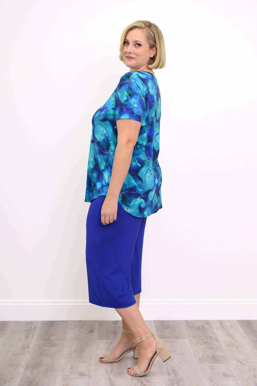 Side view of a woman in a blue floral V-neck top and blue cropped pants