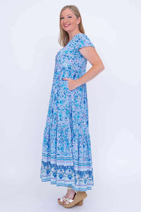 Side view of woman with hand in pocket, wearing blue floral maxi dress