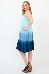 Side profile of woman in a sleeveless blue ombre dress with adjustable straps and flounce hem