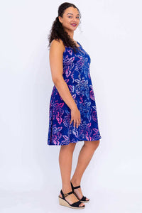 Side view of model in blue sleeveless floral dress and wedge sandals