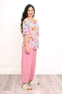 Side view of woman in bright floral blouse and pink pants