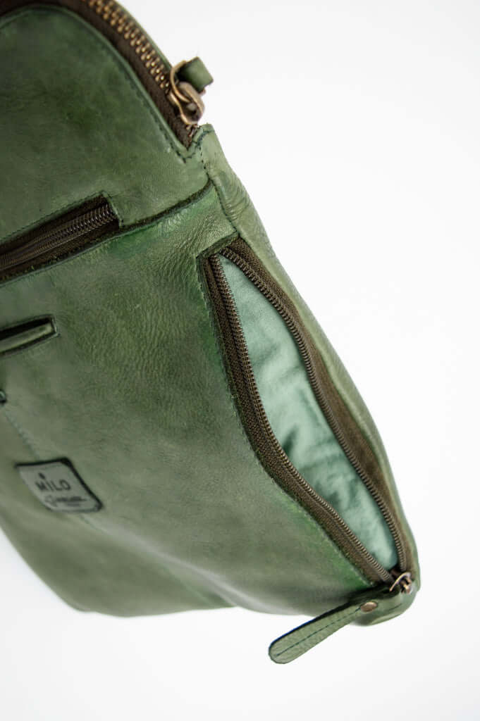 Side view of green leather crossbody bag displaying side zipper detail