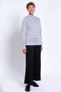 Side view of a woman in a grey button-up cardigan and black wide-leg pants