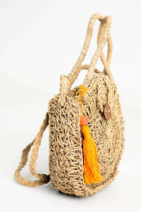 Side view of hand woven rattan bag showing orange pom-pom accent and textured weave