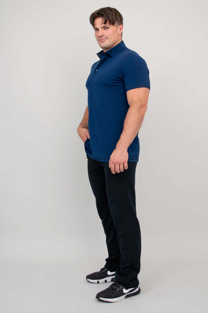 Side view of man wearing navy bamboo polo shirt and black pants