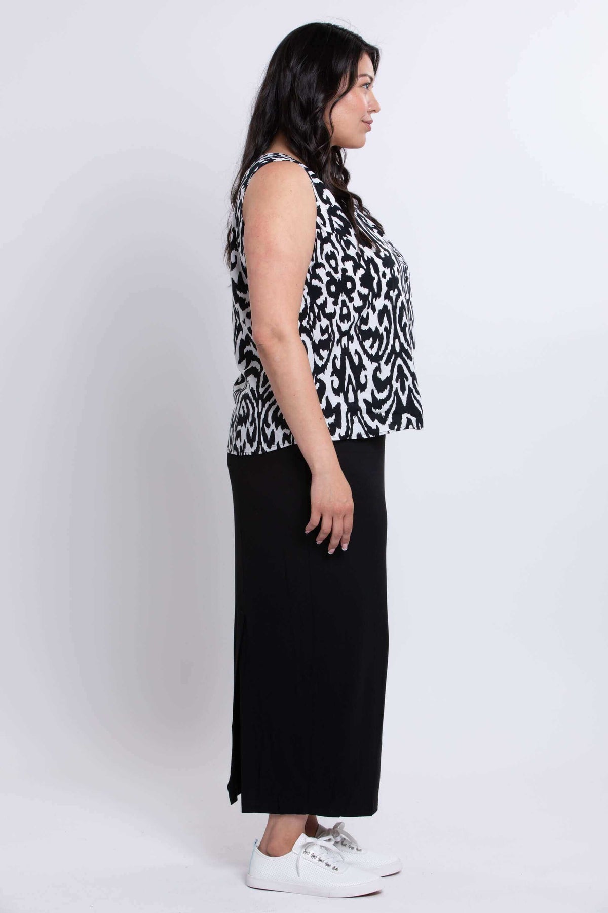 Profile view of model in sleeveless black and white Ikat tank and long black skirt