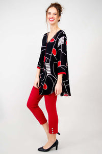 Side view of model in asymmetrical black Aku Top featuring batik print and red accents