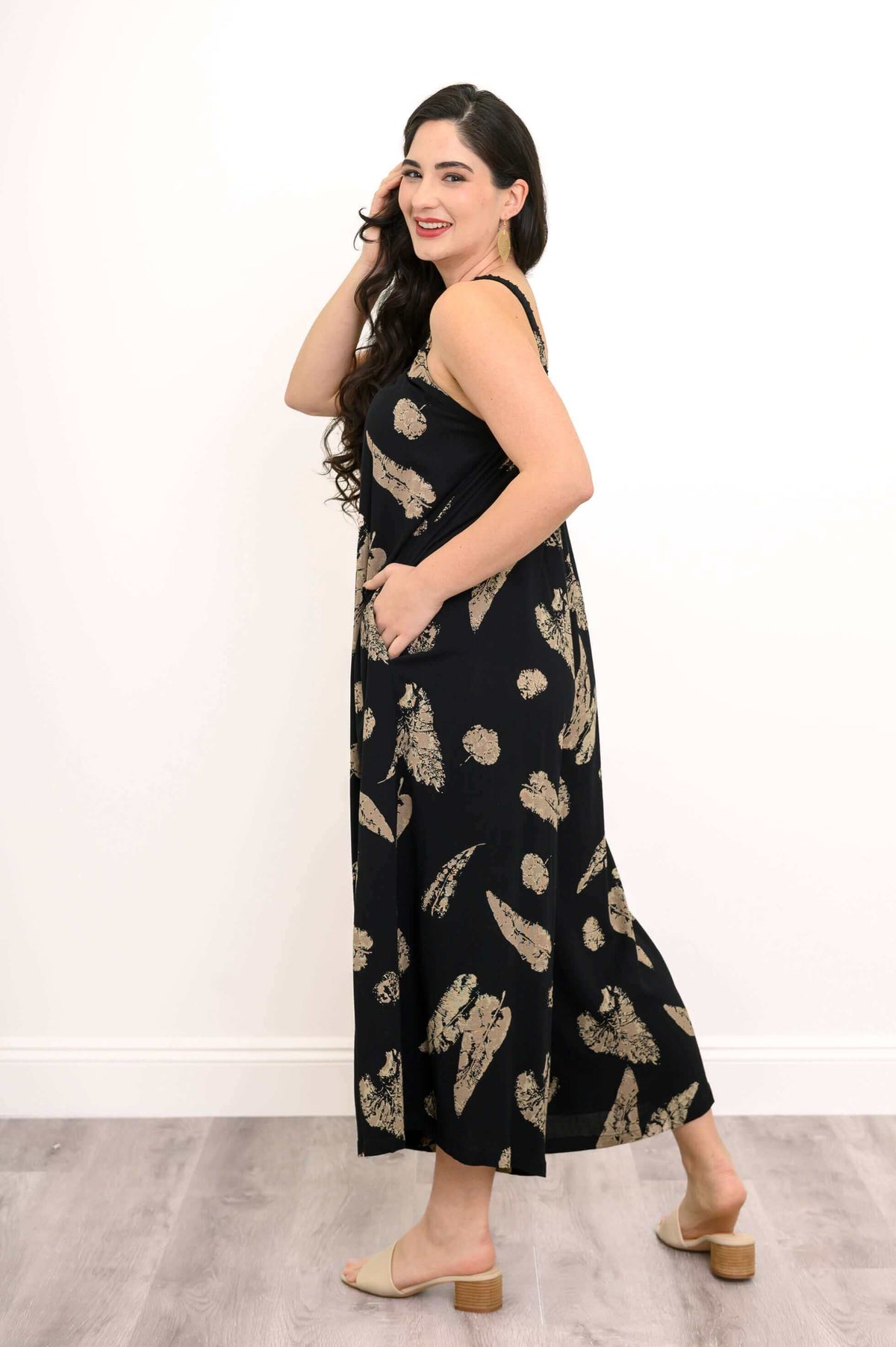 Side view of model in black jumpsuit with tan abstract print and pockets