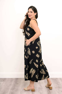 Side view of model in black jumpsuit with tan abstract print and pockets