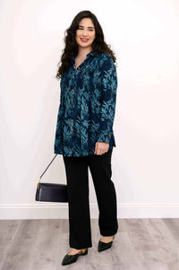 Side view of model wearing blue smocked tunic, black pants, and carrying a purse