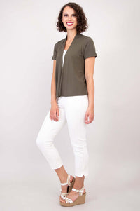 Woman in olive green short sleeve jacket and white pants viewed from side