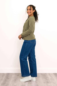 Side profile shot of a woman wearing a long sleeve olive green cable knit cashmere cardigan and blue jeans.