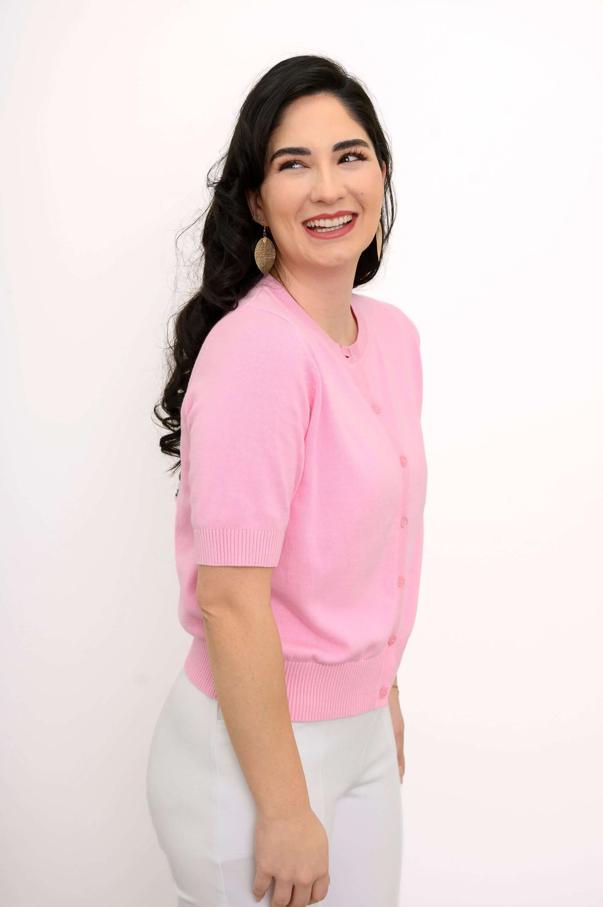 Side view of model wearing pink short-sleeve cardigan and white pants