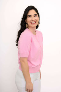 Side view of model wearing pink short-sleeve cardigan and white pants
