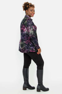 Side view of a woman wearing a printed tunic with smocking paired with black pants and boots