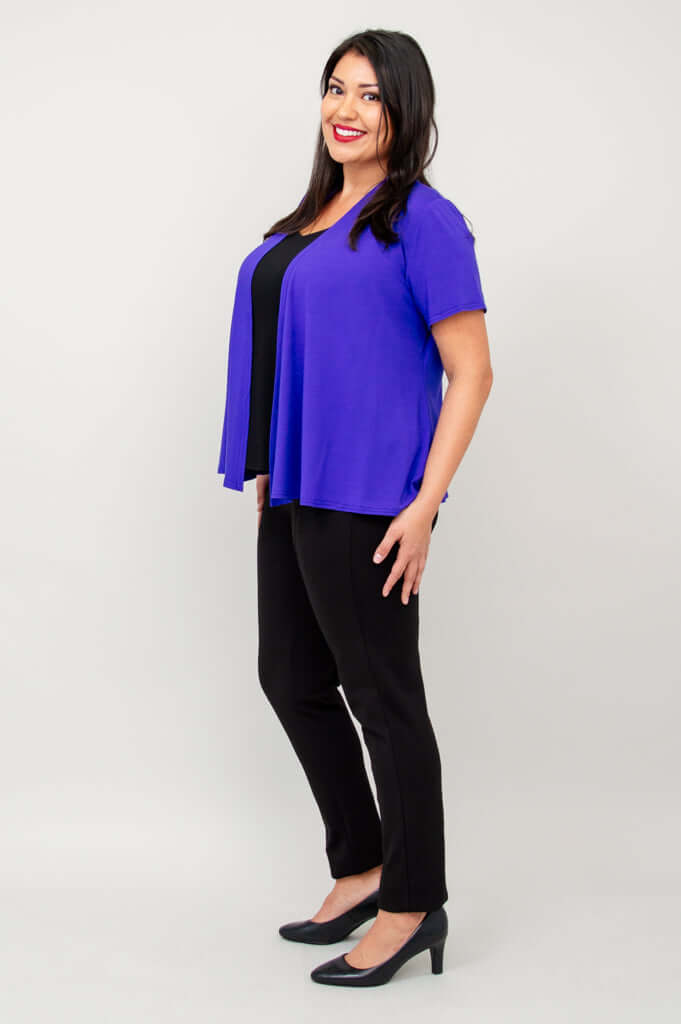 Side view of model in purple short sleeve open jacket over black top and pants