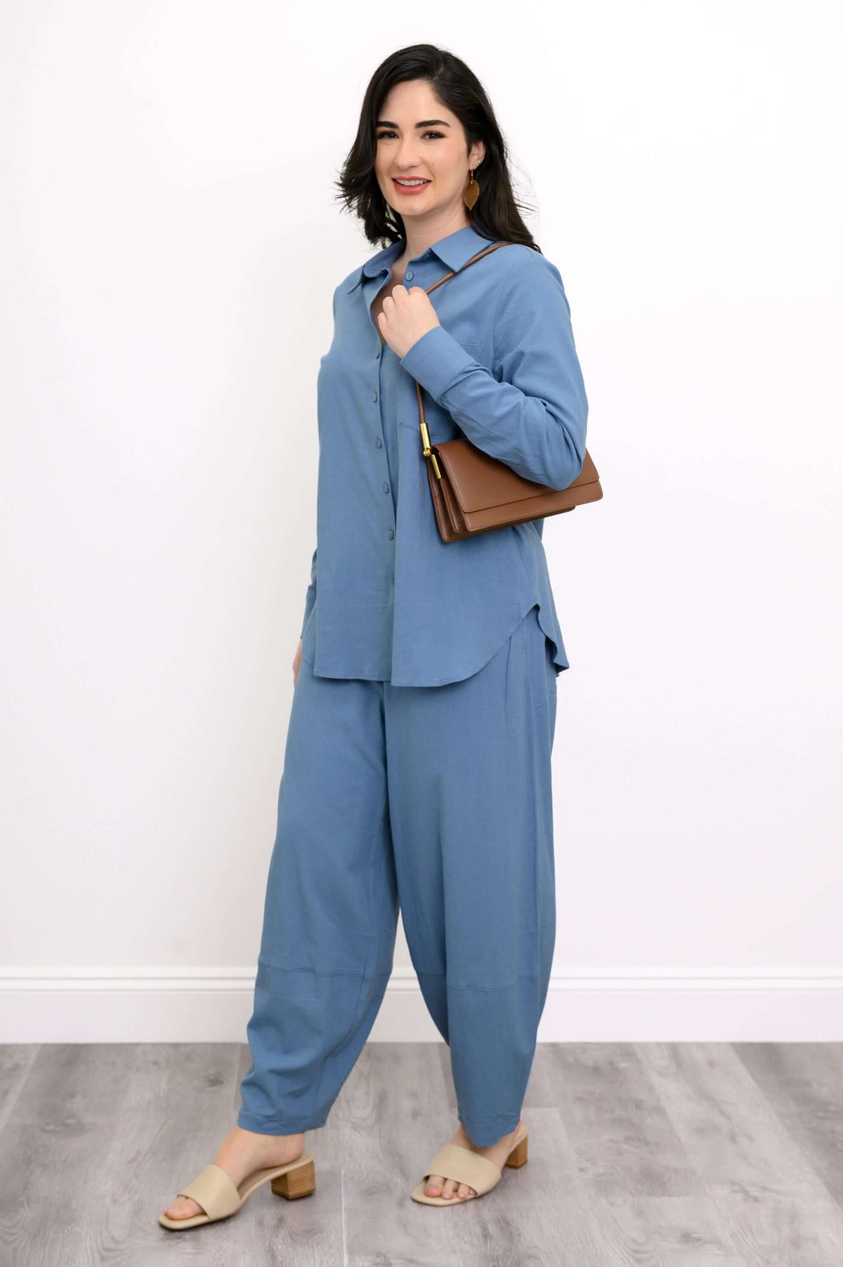 Side view of woman in sky blue shirt and pants with brown shoulder bag