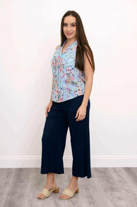 Woman modeling a sleeveless floral shirt and navy capri pants, side view