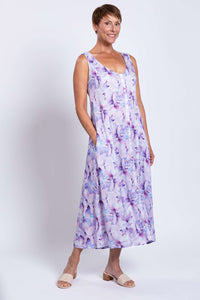 Woman showing side pockets of a sleeveless watercolor maxi dress