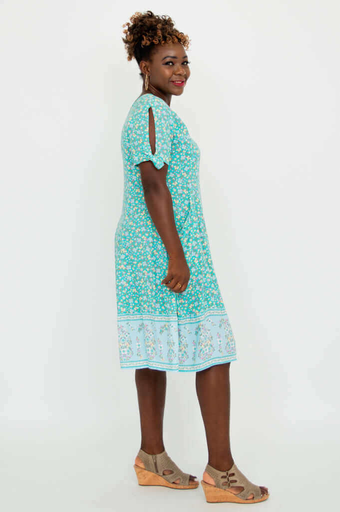 Side profile of a woman in a teal floral dress with tie sleeve detail