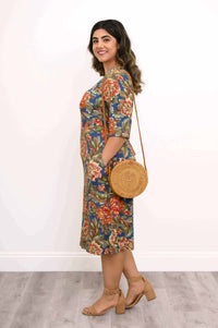 Side view of woman in blue floral bamboo dress with a round straw crossbody bag