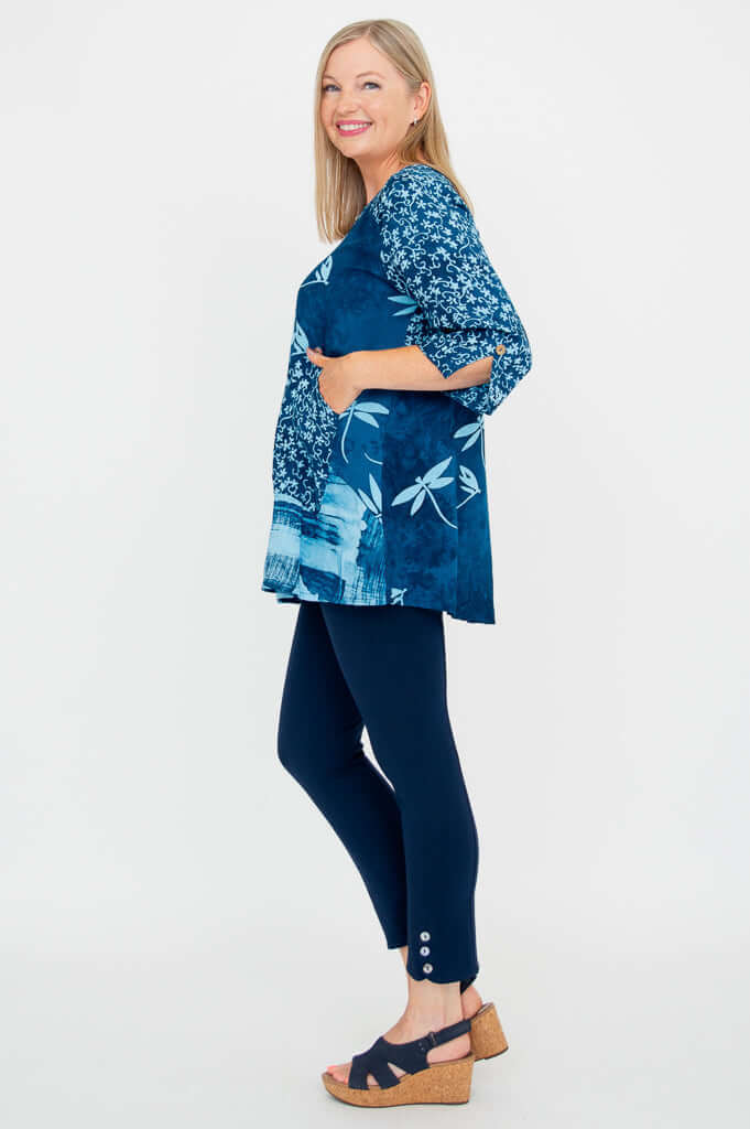 Side view of woman in blue patterned blouse with scoop neckline and single pocket