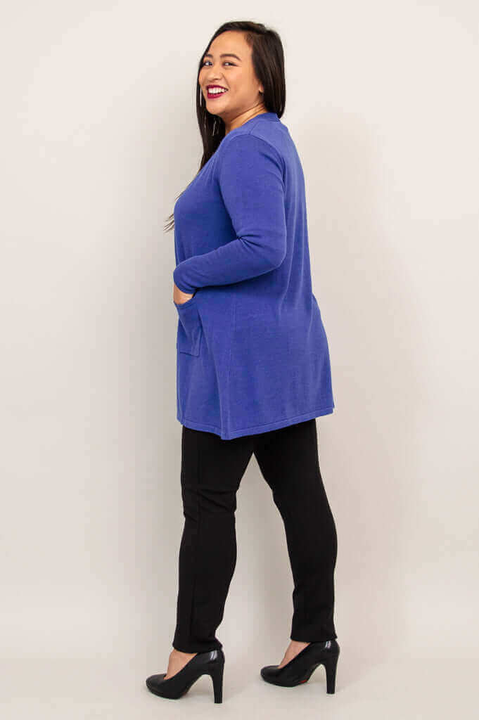 Side view of a woman wearing a royal blue mid-thigh cardigan with pockets