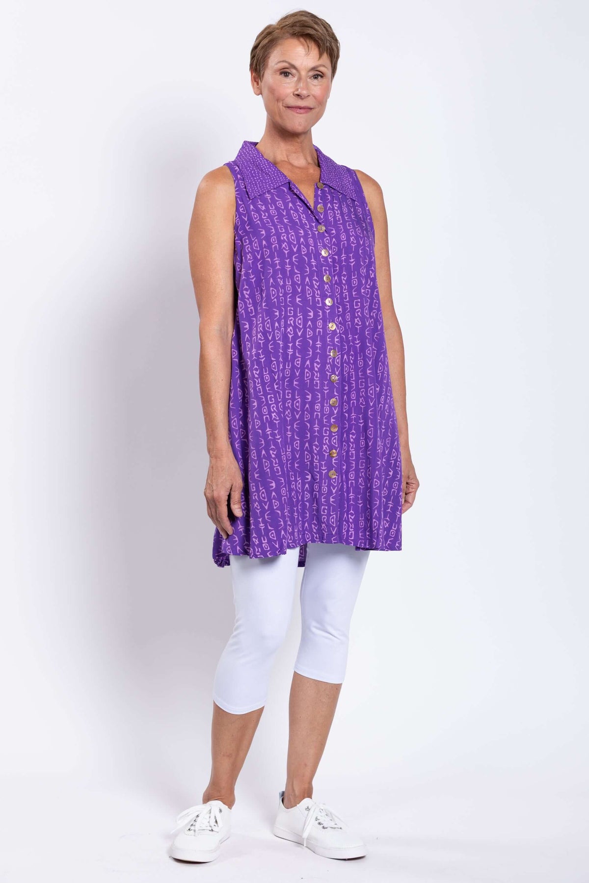 Full-body side view of woman in purple A-line swing tank and white capri leggings