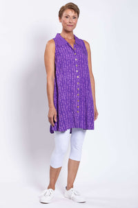 Full-body side view of woman in purple A-line swing tank and white capri leggings
