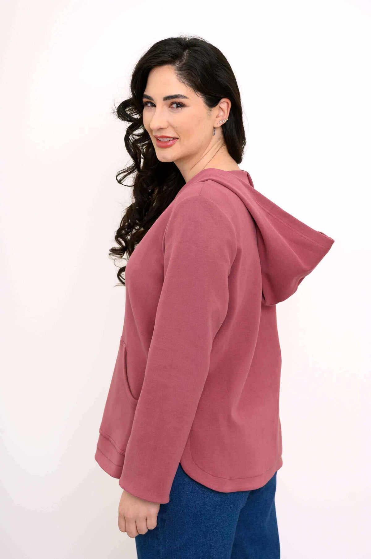 Side view of woman modeling a rose-colored hoodie jacket with a relaxed fit
