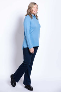 Side view of woman walking in light blue sweater and navy pants