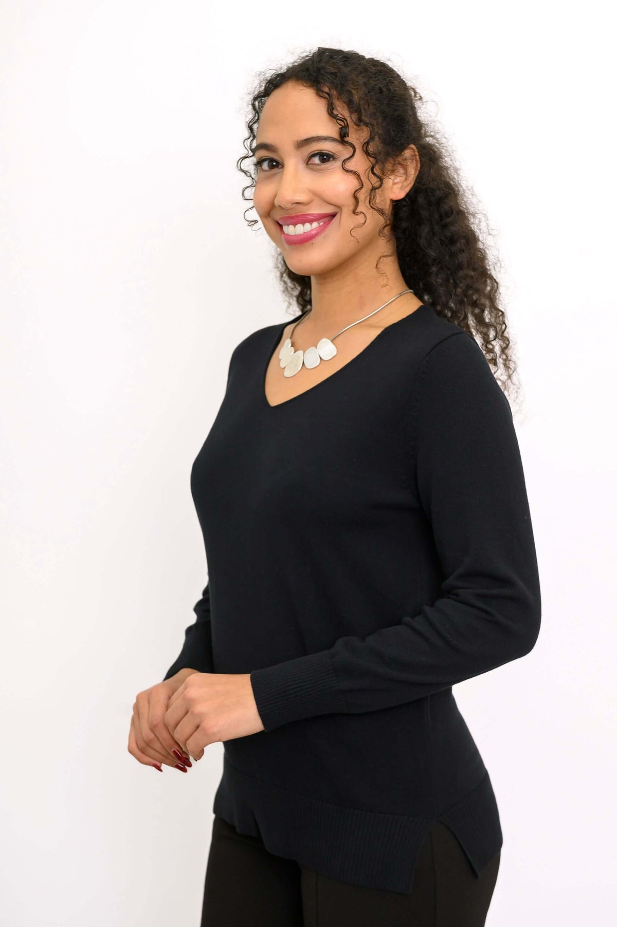 Side view of woman wearing a black V-neck sweater, showing hem side slits