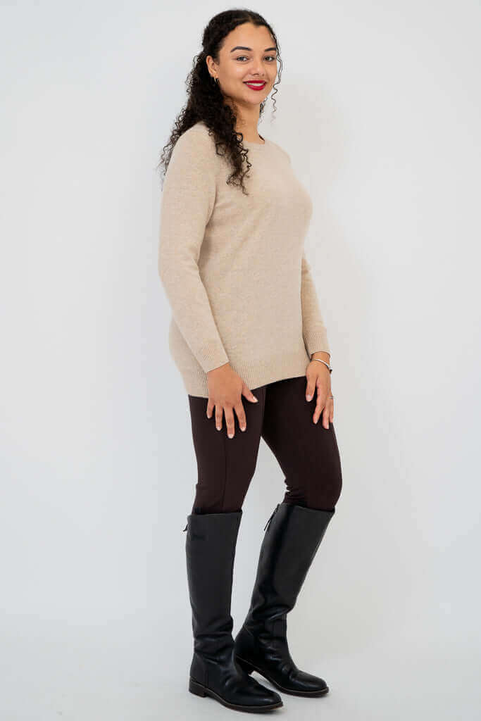 Side view of woman wearing beige sweater and black boots